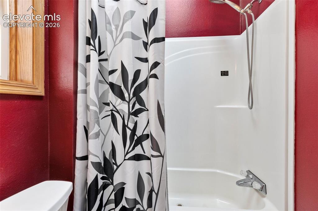 Image 35 of 45: White fiberglass tub and shower combination with a curved basin and chrome