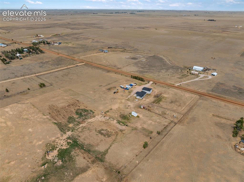 Image 45 of 45: Expansive rural landscape featuring a single-story residence with a dark ro