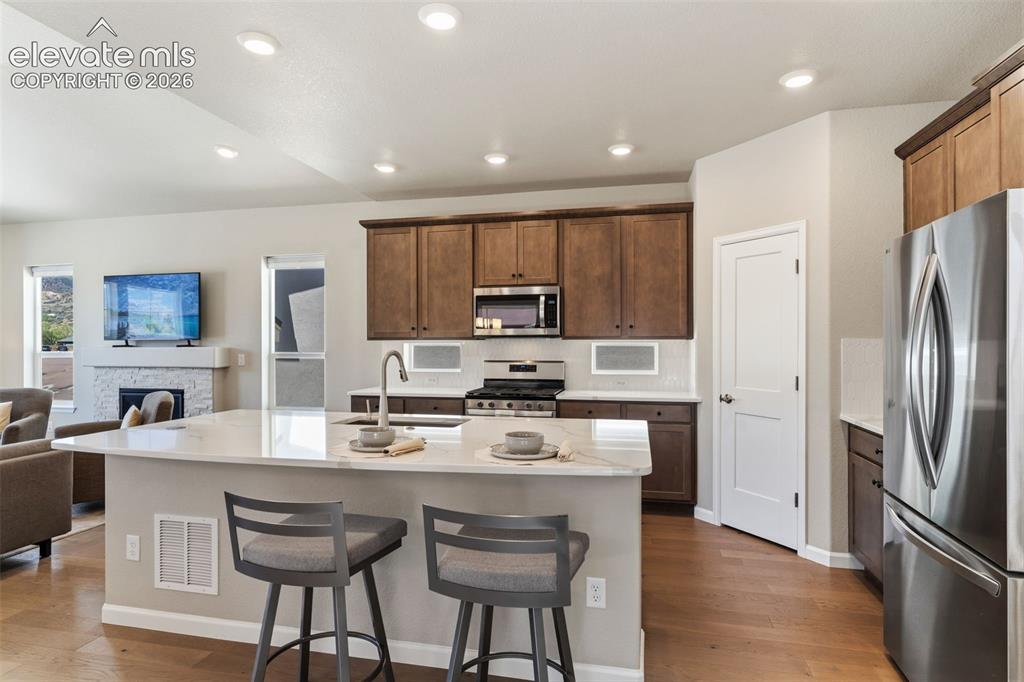 Image 11 of 41: Open-concept kitchen featuring an island with a light-toned countertop, woo