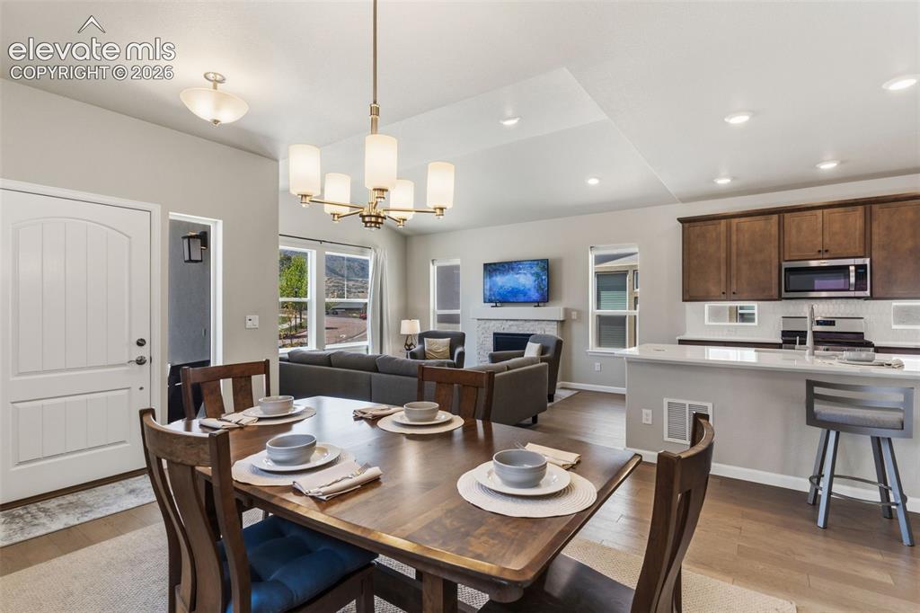 Image 16 of 41: Dining area featuring a wood-finish dining table, a brushed brass chandelie