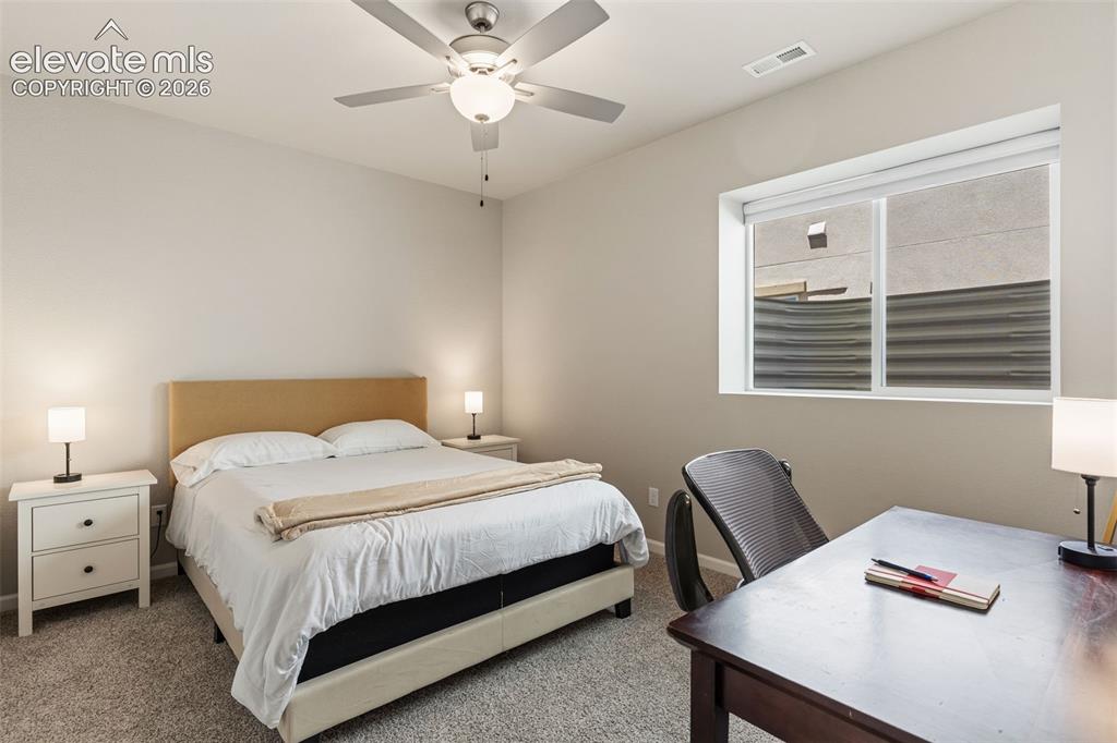 Image 21 of 41: Carpeted room featuring a light beige upholstered headboard, white side tab