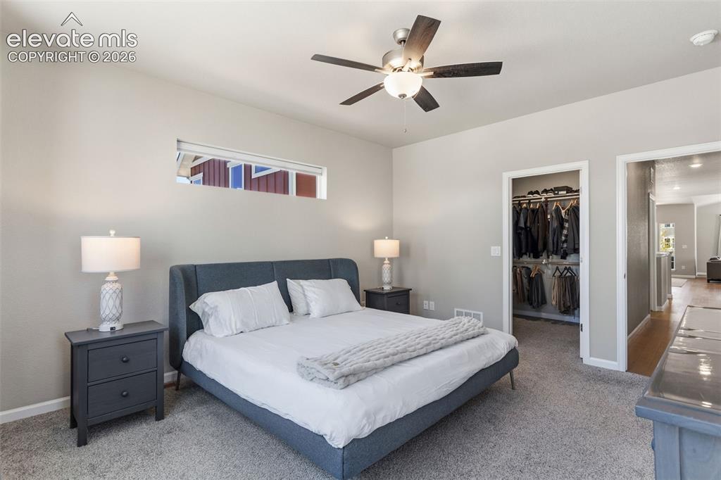 Image 24 of 41: Carpeted sleeping area with a ceiling fan light fixture, high window, and n