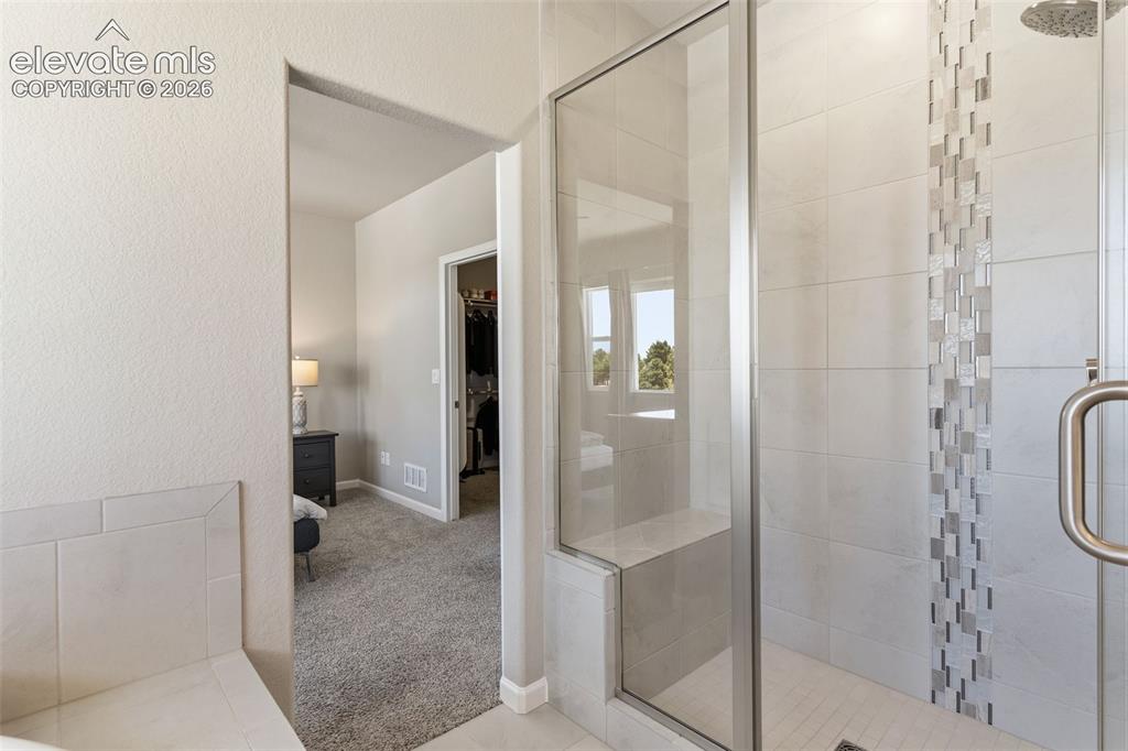Image 27 of 41: Glass-enclosed shower featuring a tiled bench and a decorative tile accent