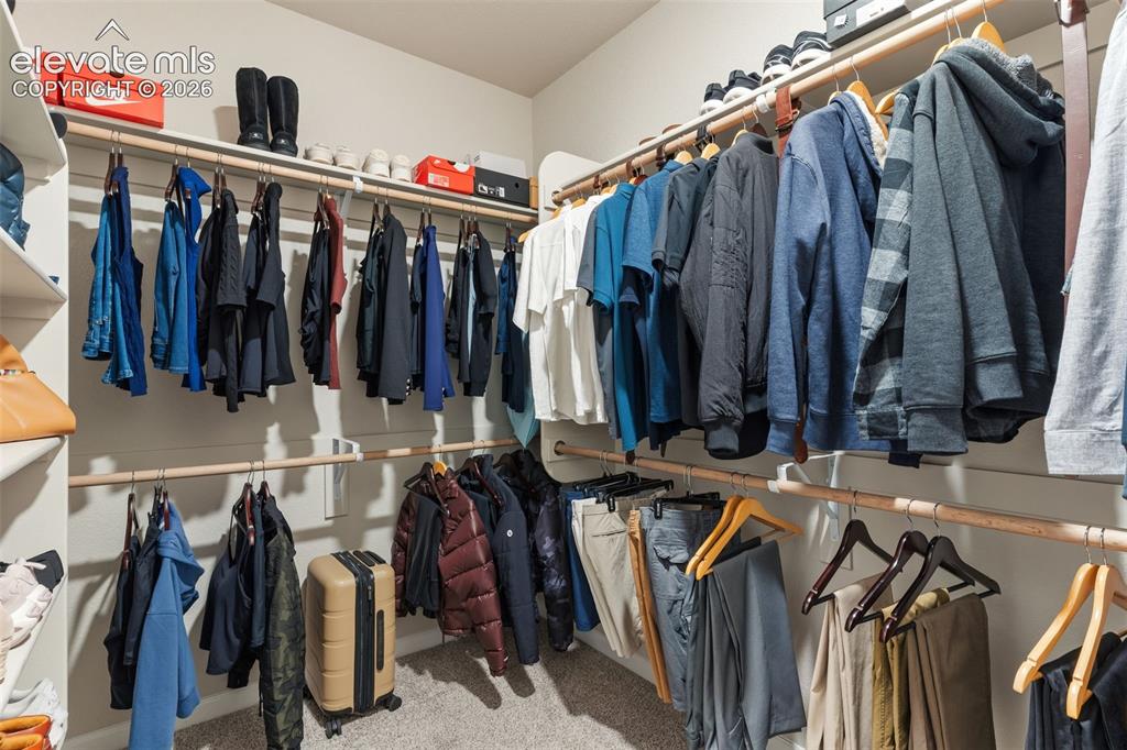 Image 28 of 41: Built-in closet system featuring multiple hanging rods, overhead shelving,