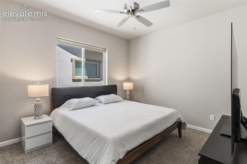 Image 29 of 41: Carpeted bedroom featuring a contemporary ceiling fan, white window treatme