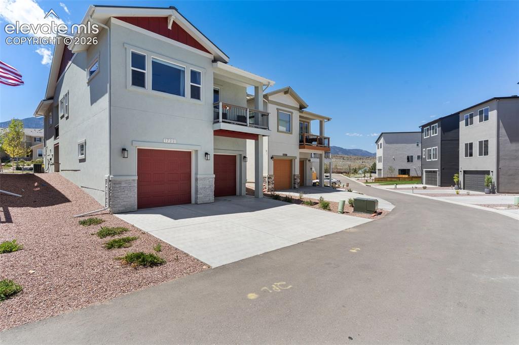 Image 3 of 41: Contemporary multi-level exterior with a light stucco finish, red garage do
