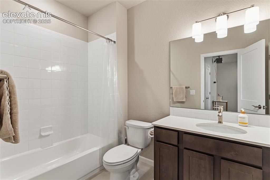 Image 31 of 41: Bathroom featuring a full-size tub with white subway tile surround, a dark