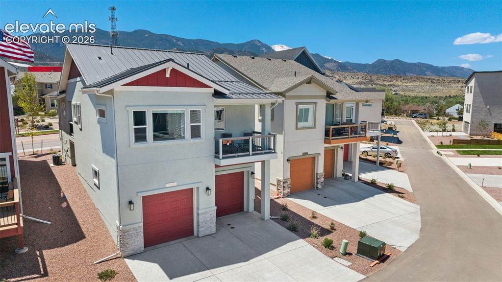 Image 40 of 41: Modern multi-level townhome featuring a metal roof, contrasting red garage