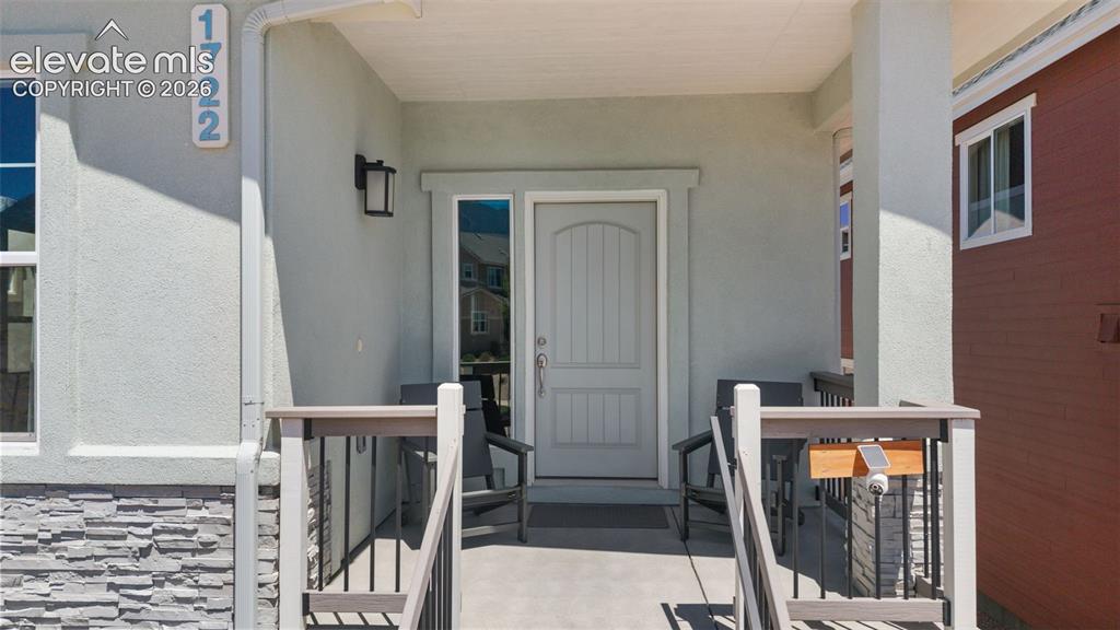 Image 6 of 41: Covered porch entrance featuring a paneled door with sidelight, stacked sto