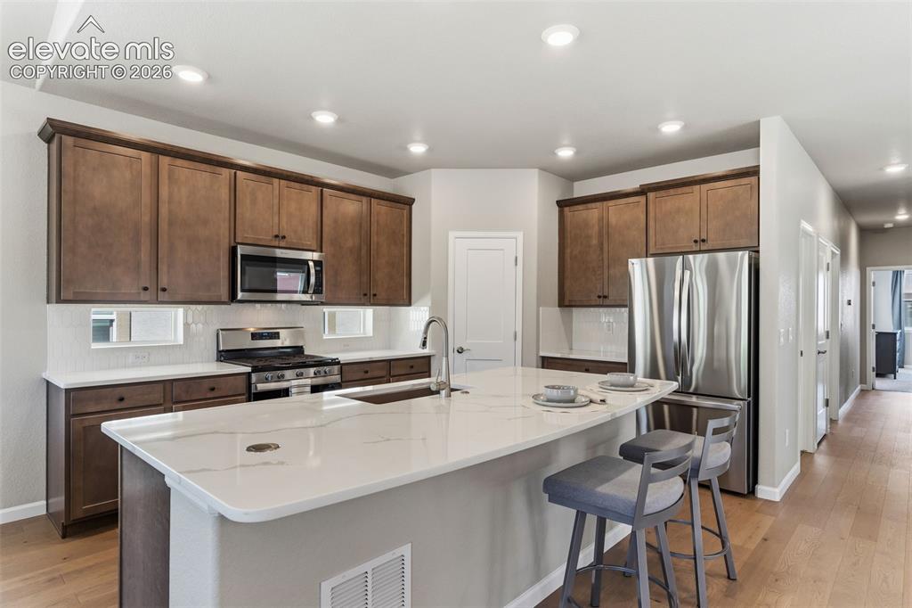 Image 9 of 41: Spacious kitchen featuring an expansive island with white stone-finish coun