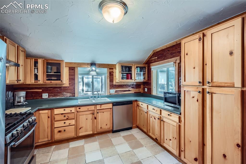Image 11 of 20: Kitchen with appliances with stainless steel finishes, a sink, dark counter