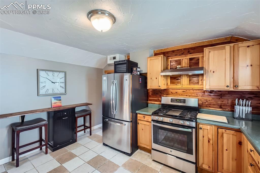 Image 13 of 20: Kitchen featuring stainless steel appliances, under cabinet range hood, vau