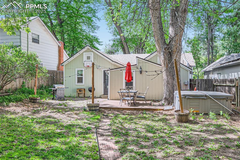 Image 18 of 20: Back of property with a hot tub, a deck, and roof with shingles
