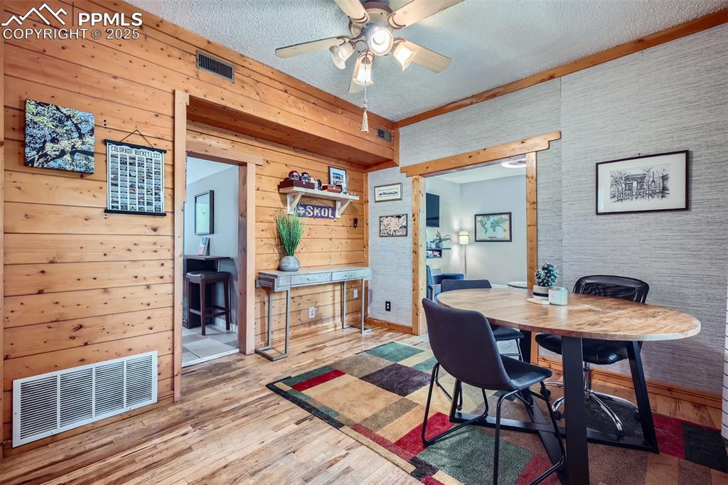 Image 4 of 20: Dining room featuring ceiling fan, wood finished floors, wooden walls, a te