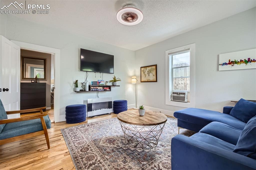 Image 6 of 20: Living room featuring wood finished floors, a textured ceiling, cooling uni