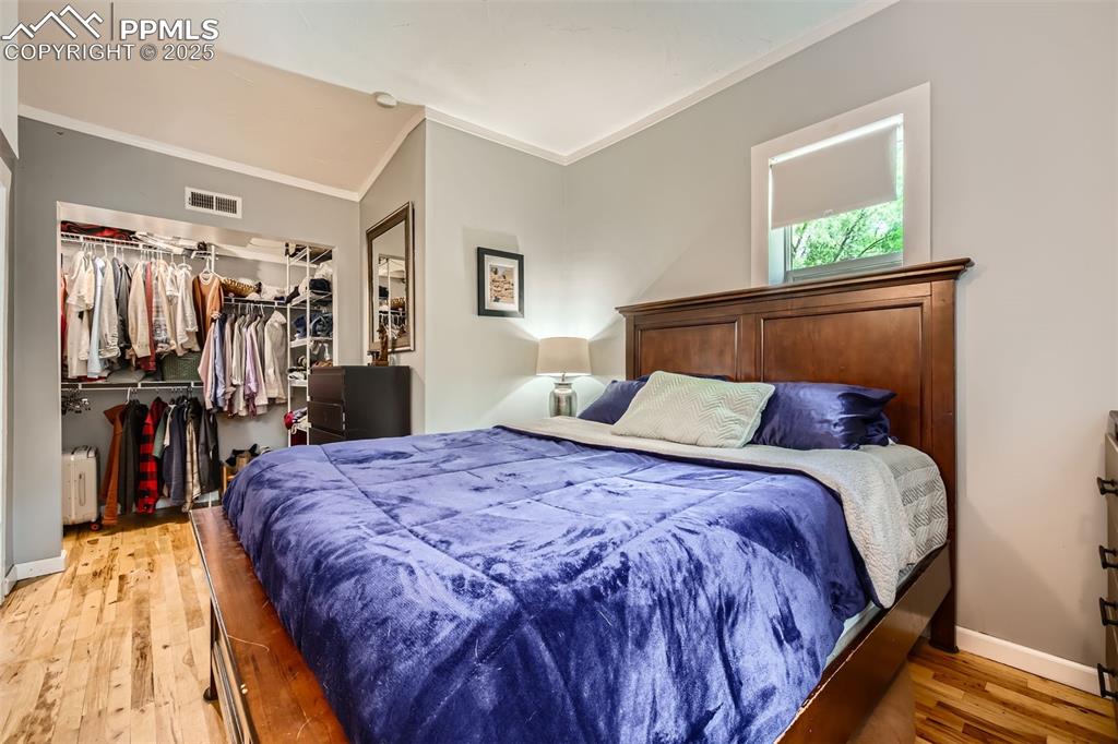 Image 7 of 20: Bedroom with ornamental molding, light wood-style floors, a closet, a walk 