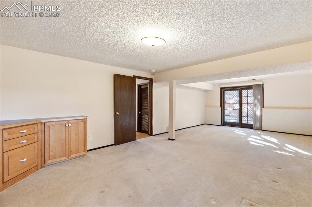 Image 35 of 42: Basement Family Room with built in cabintry and walk-out to patio. 