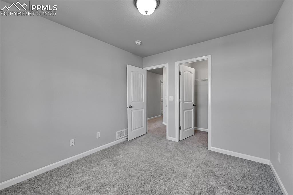 Image 30 of 46: Unfurnished bedroom with a walk in closet and light carpet