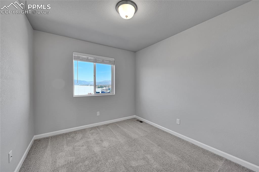 Image 33 of 46: Empty room featuring a mountain view and light carpet