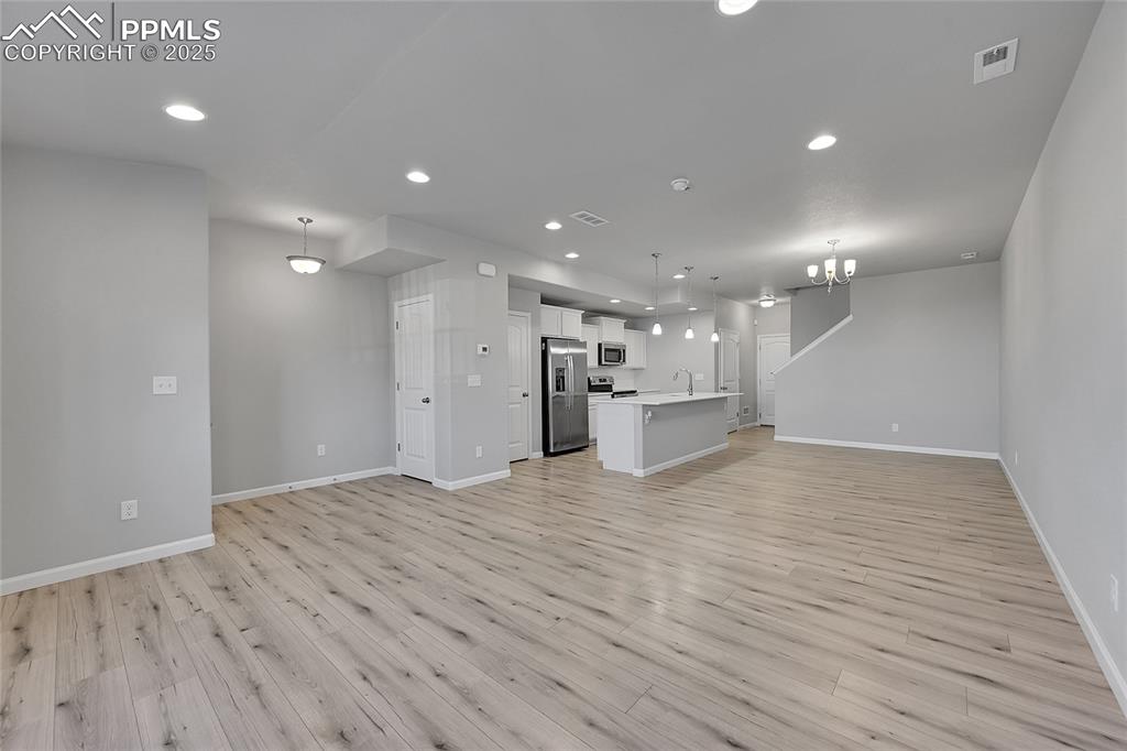 Image 9 of 46: Unfurnished living room with a chandelier, light wood-type flooring, and re