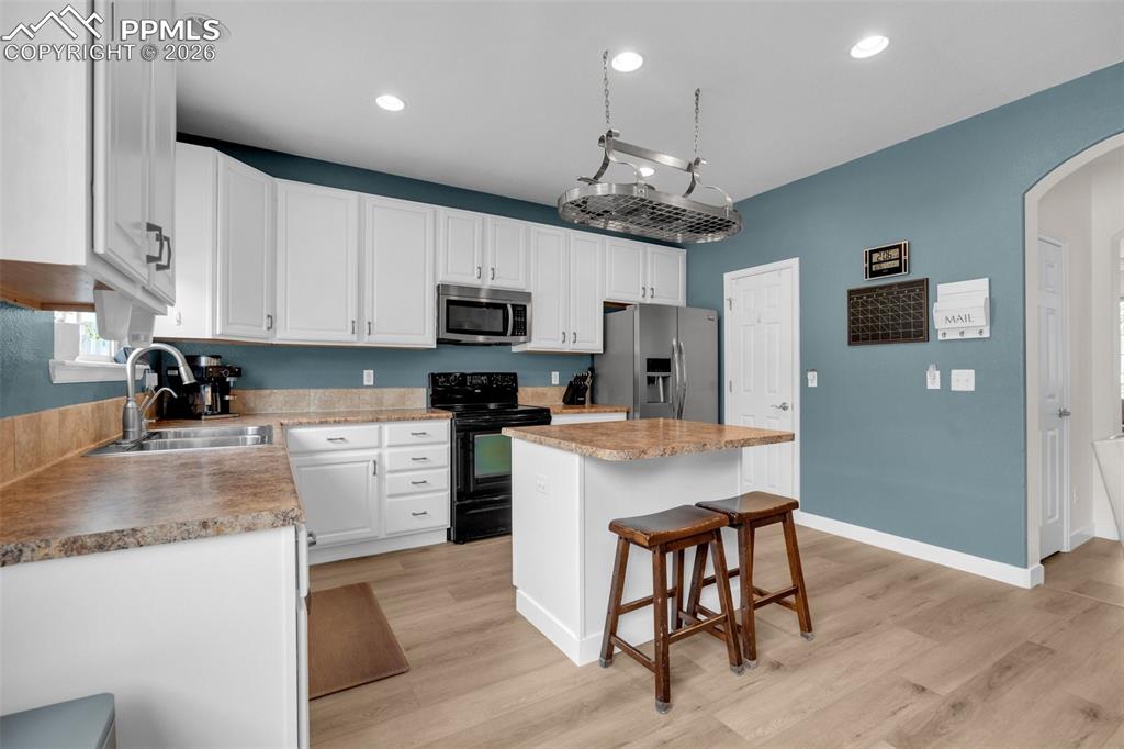 Image 12 of 39: Dining space featuring arched walkways and light wood-style floors