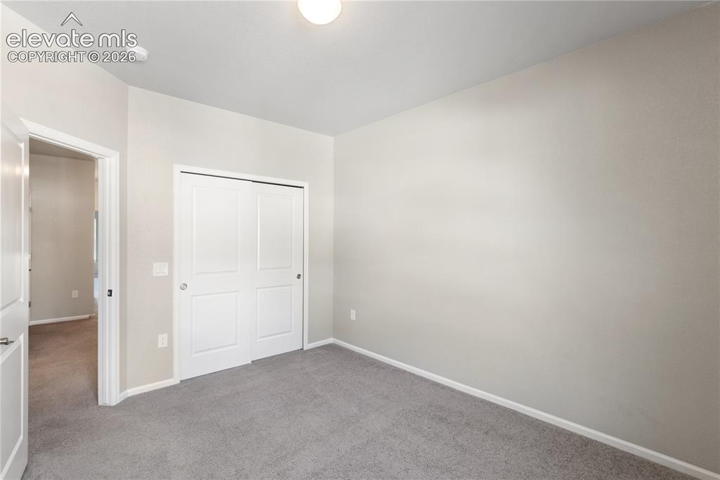 Image 10 of 19: Carpeted room featuring a white bi-fold closet, light-toned walls, white tr