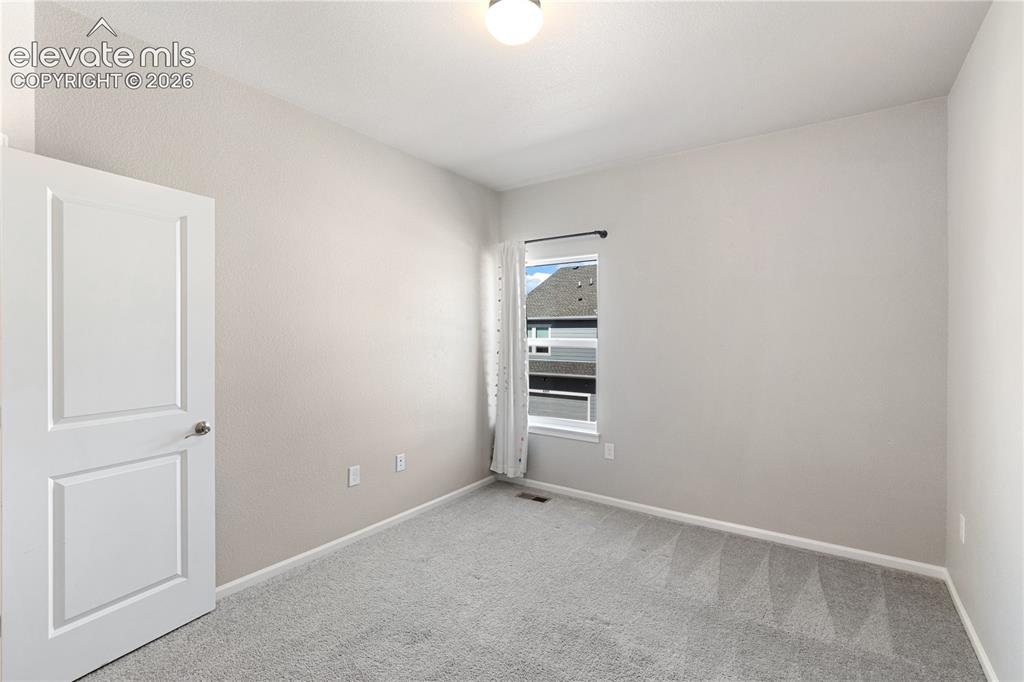 Image 12 of 19: Bright room featuring light gray carpet flooring, neutral painted walls, an