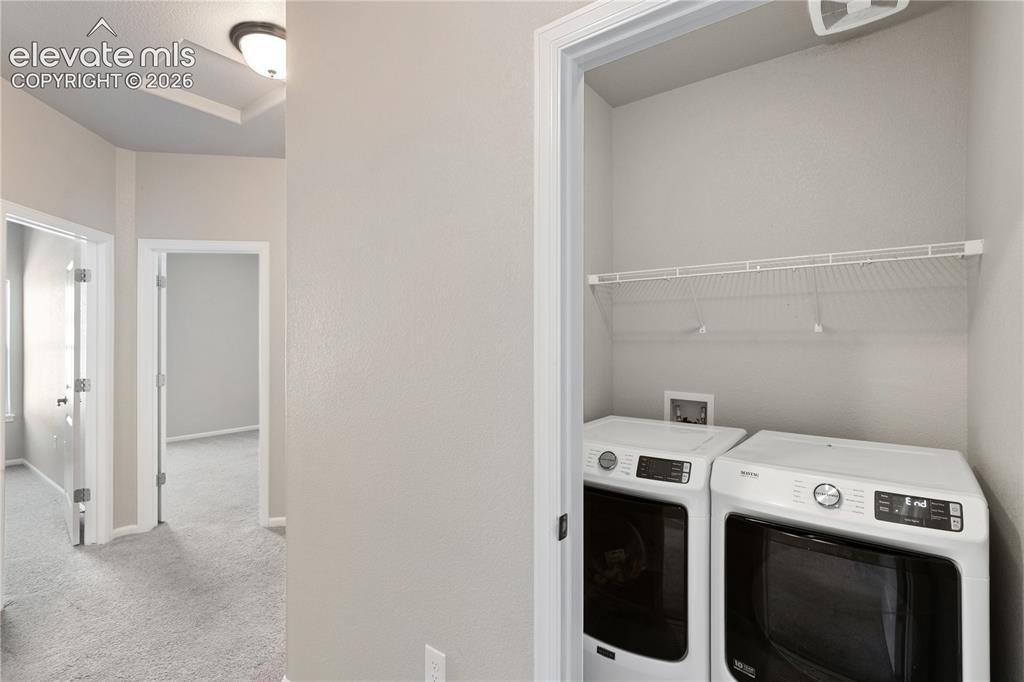 Image 14 of 19: Dedicated laundry closet featuring a wire storage shelf and light gray wall