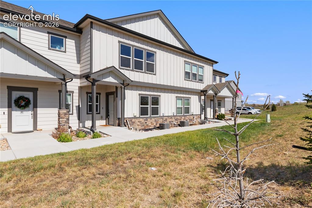 Image 2 of 19: Modern townhome exterior featuring light-colored siding, dark trim, stone a