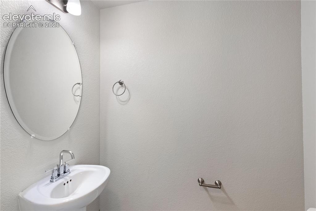 Image 8 of 19: Pedestal sink with chrome faucet, complemented by an oval frameless mirror