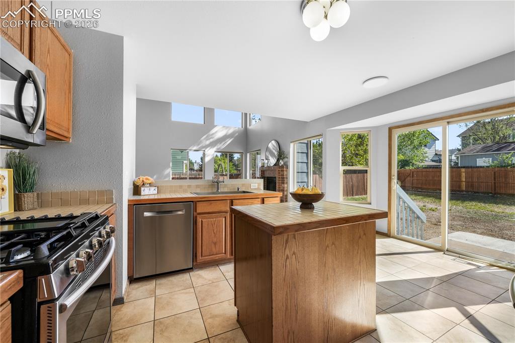Image 12 of 50: Kitchen with newer stainless steel applicants, island, pantry and walk out