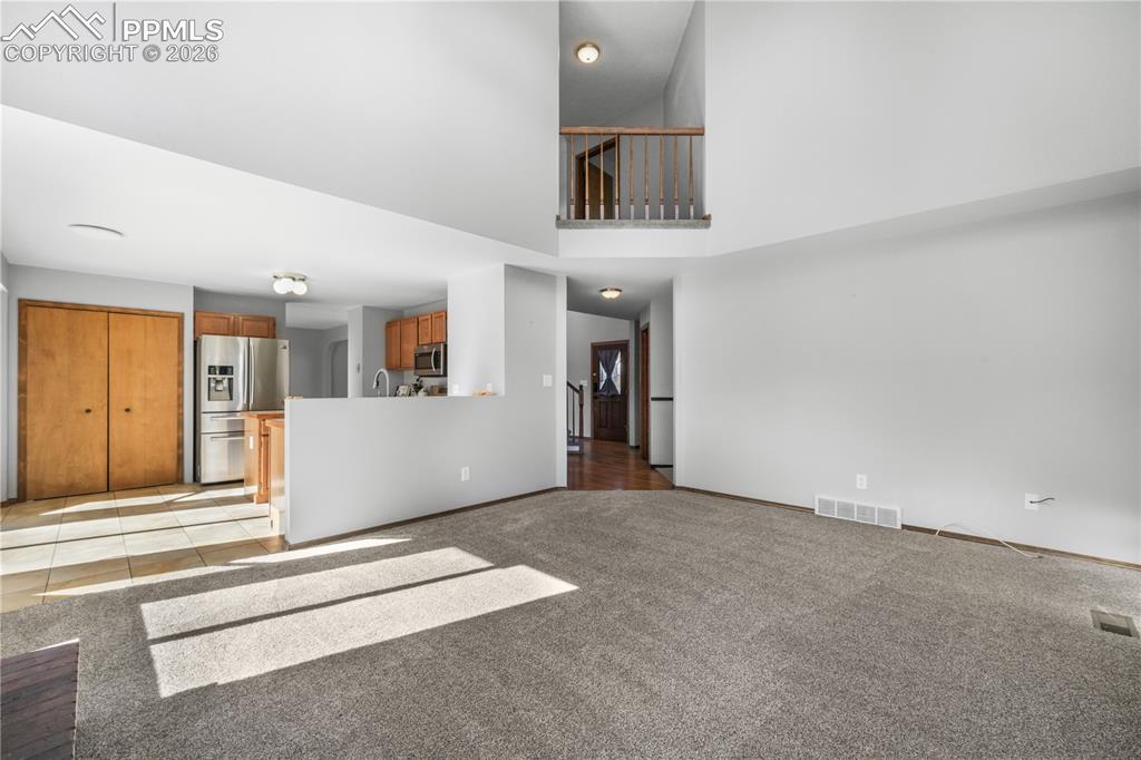 Image 17 of 50: Main level living room with wood burning fireplace, vaulted ceilings and ab