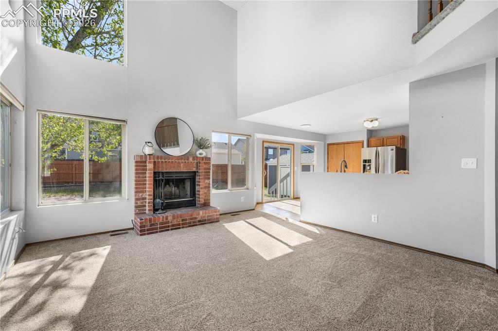 Image 18 of 50: Main level living room with wood burning fireplace, vaulted ceilings and ab