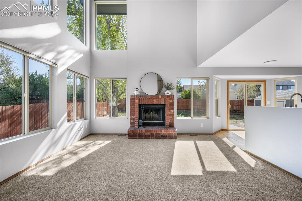 Image 19 of 50: Main level living room with wood burning fireplace, vaulted ceilings and ab