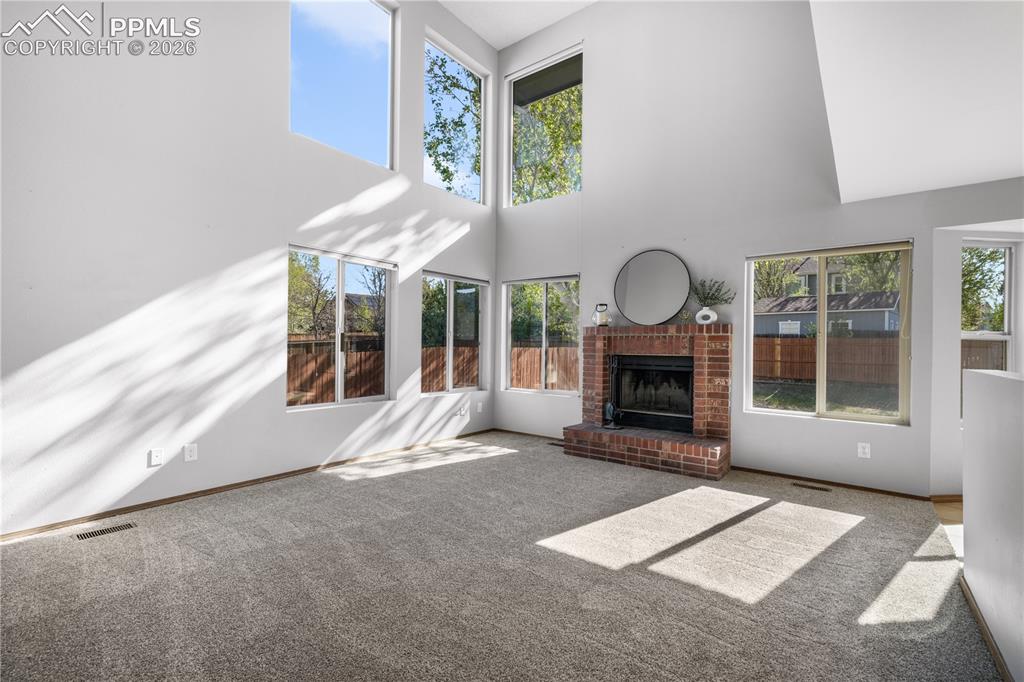 Image 20 of 50: Main level living room with wood burning fireplace, vaulted ceilings and ab