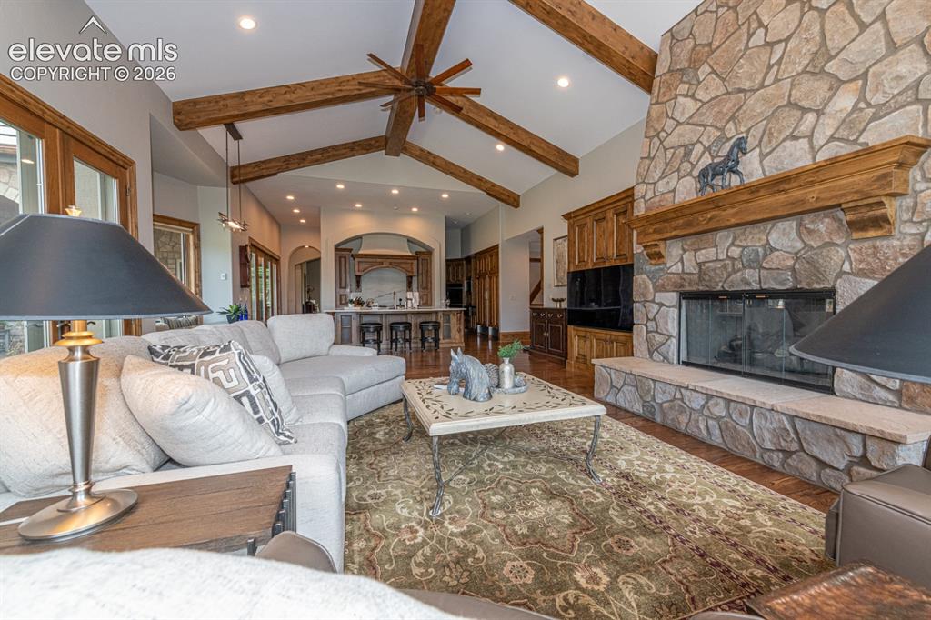 Image 16 of 50: Great room with stone fireplace looking back to the kitchen