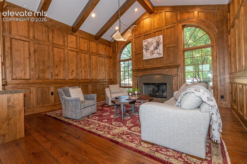Image 6 of 50: Front sitting room with beamed ceiling, fireplace, and alder wanescoating