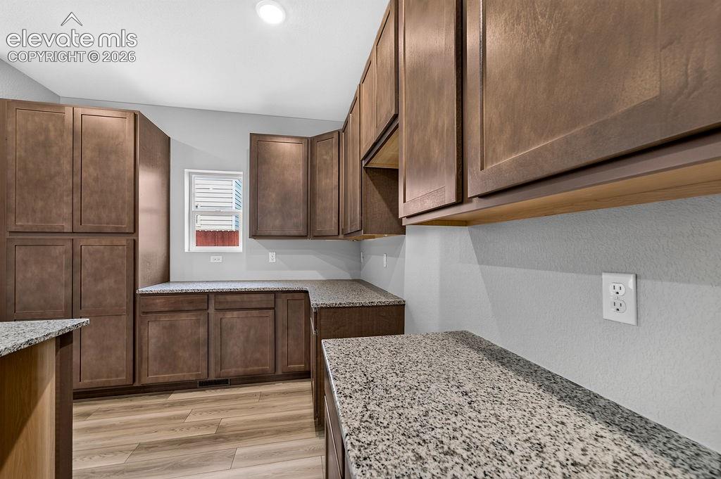 Image 11 of 33: Spacious kitchen featuring extensive wood-finish cabinetry, light-toned gra