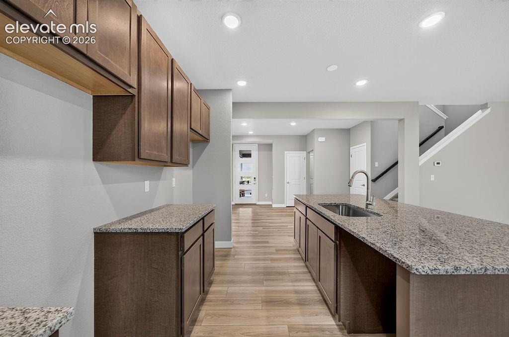 Image 12 of 33: Spacious kitchen featuring an island with an undermount sink, brown wood-fi