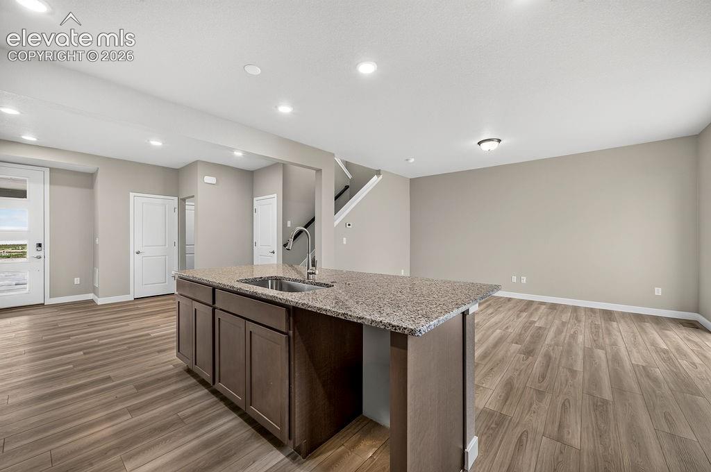 Image 13 of 33: Kitchen island with a stainless steel sink and granite countertop, wood-fin