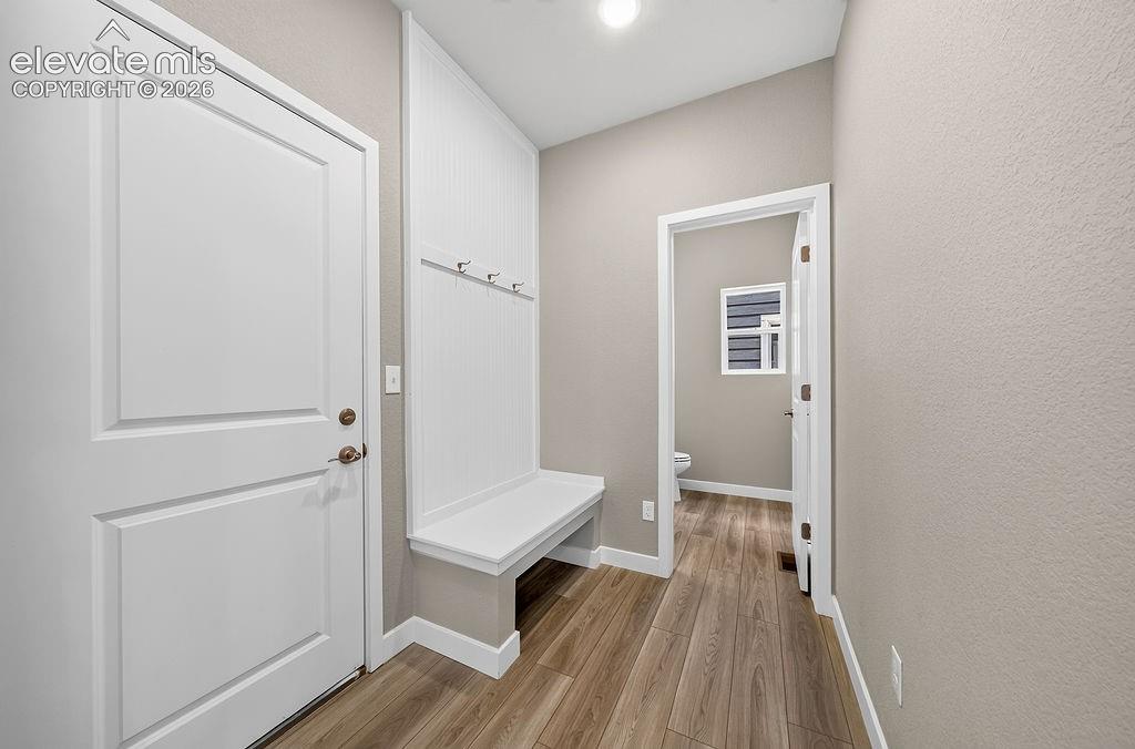 Image 17 of 33: Wood-finish flooring throughout, white paneled door, built-in white bench,