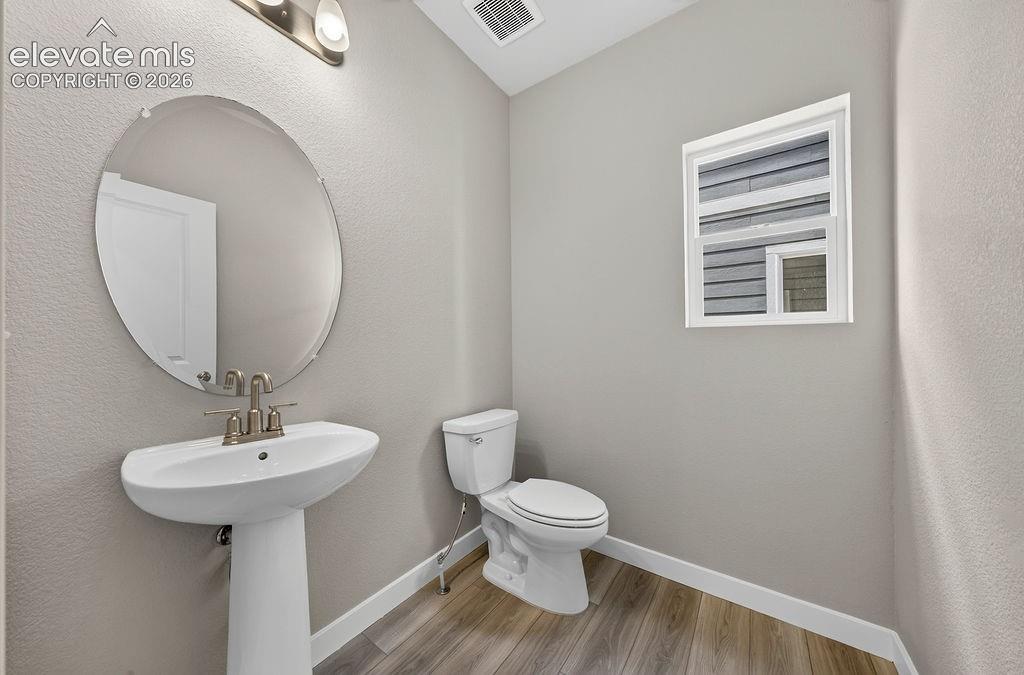 Image 18 of 33: Pedestal sink with a brushed nickel faucet, oval wall mirror, wood-finish f