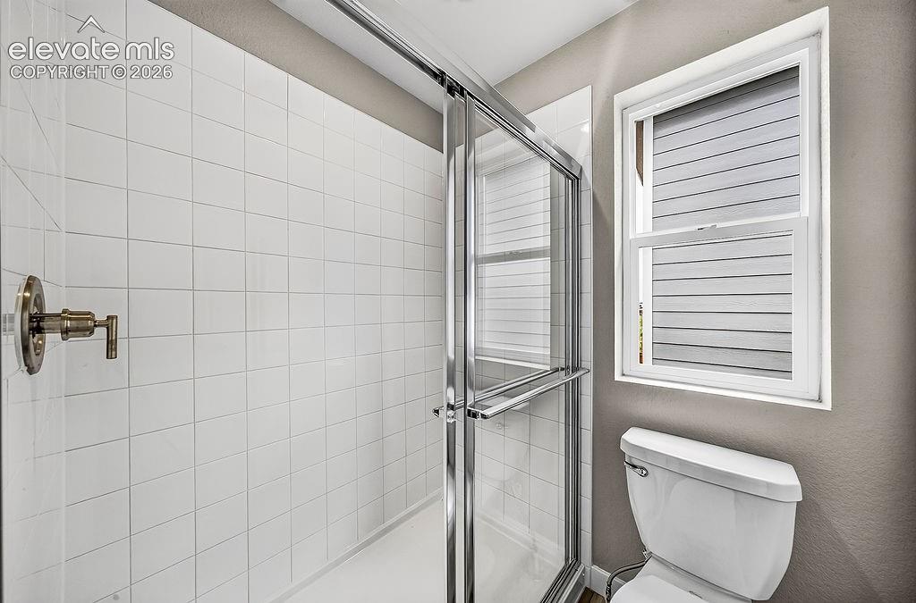 Image 23 of 33: Shower enclosure with sliding glass door, white square tile surround, and b