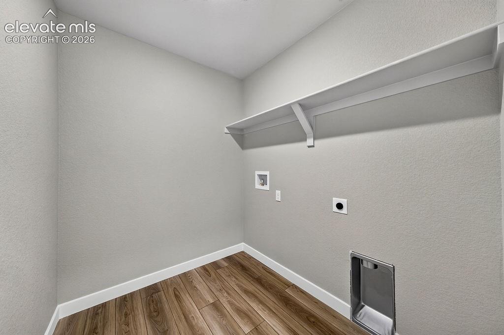 Image 26 of 33: Wood-finish flooring with white trim, light gray walls, and an integrated w