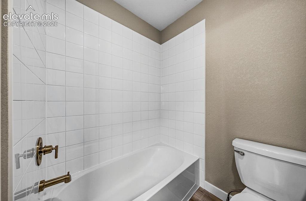 Image 28 of 33: Built-in bathtub with subway tile surround and bronze-finish fixtures