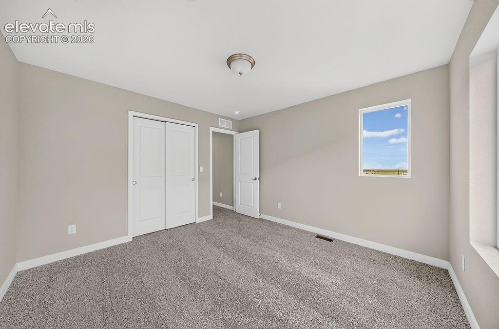 Image 32 of 33: Carpeted room with neutral wall tones, a double-door closet, an interior do