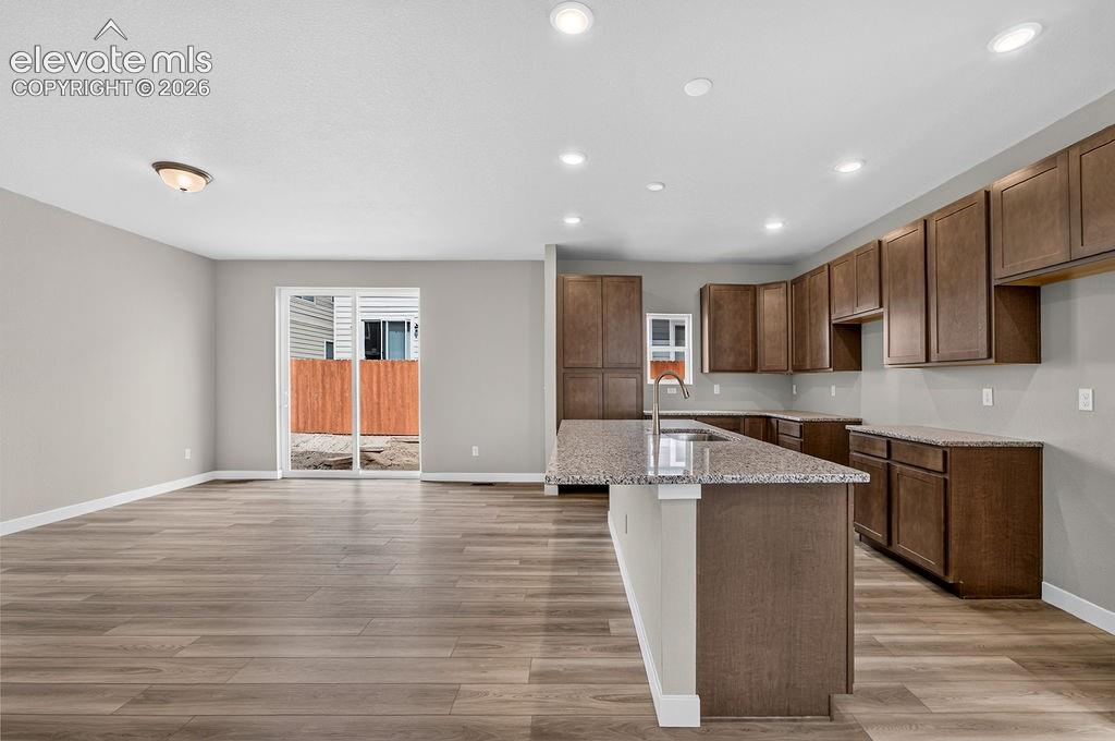 Image 9 of 33: Contemporary kitchen featuring wood-finish cabinetry, granite countertops,