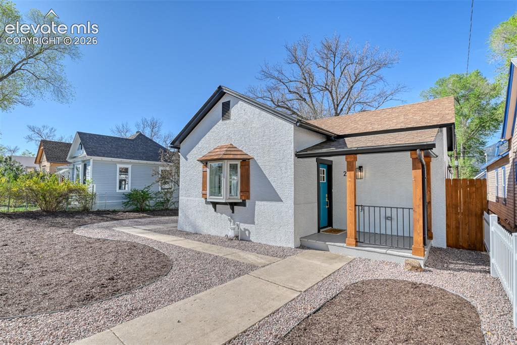 Image 1 of 47: White stucco exterior featuring a turquoise front door, covered porch with 