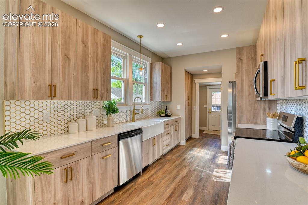 Image 17 of 47: Modern kitchen featuring wood-finish cabinetry, white countertops, and a wh