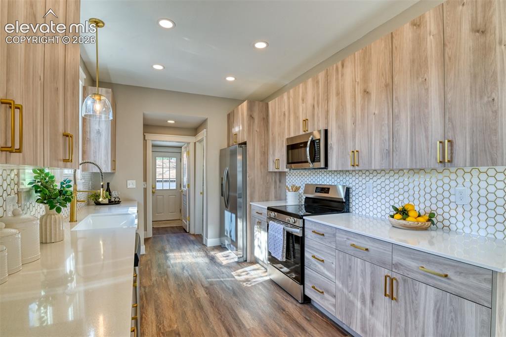 Image 18 of 47: Contemporary kitchen featuring wood-finish cabinetry with gold-tone hardwar